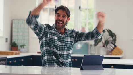 Celebrando-Al-Hombre-Con-Tarjeta-De-Crédito-Usando-Una-Tableta-Digital-En-Casa-Para-Reservar-Vacaciones-O-Comprar