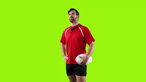 professional rugby player standing and holding a ball on green background 4k