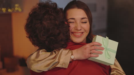 happy woman hugging someone while holding a gift