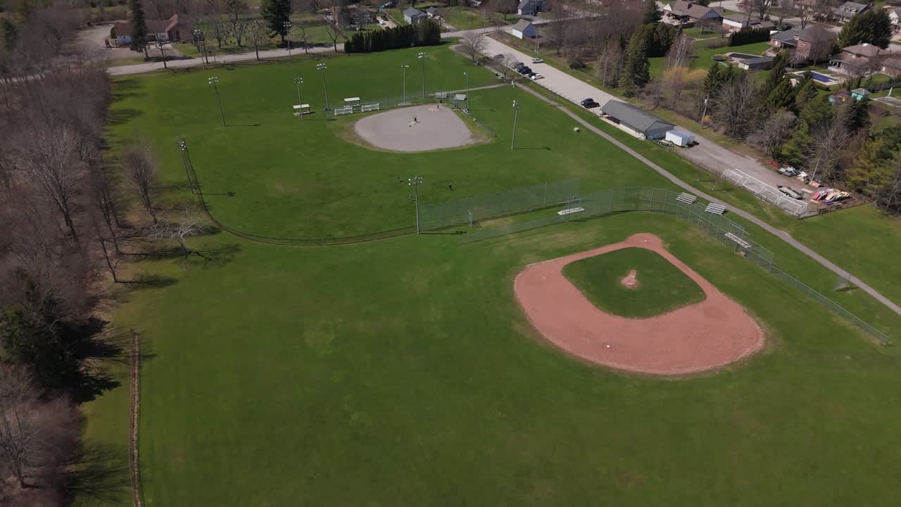 Drone che vola all'indietro rivelando campi da baseball in un parco pubblico.