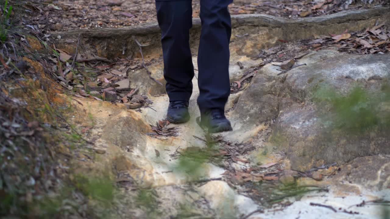 Close up of a woman's hiking boots walking down a dirt trail
