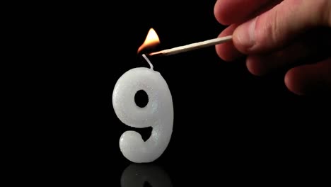 Animation-of-burning-antique-document-over-number-9-lit-birthday-candle-on-black-background