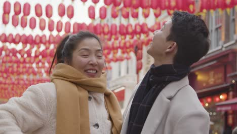 Joven-Pareja-Asiática-De-Vacaciones-Posando-Para-Selfie-En-Teléfono-Móvil-En-Chinatown,-Londres,-Reino-Unido-5