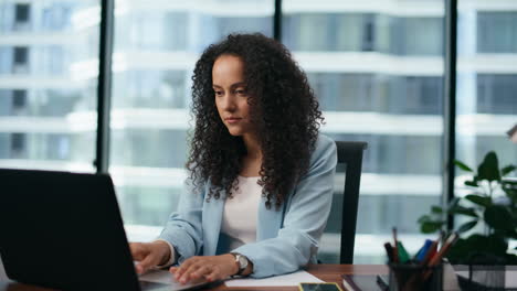 Portrait-businesswoman-typing-laptop-sitting-office.-Woman-working-on-computer.