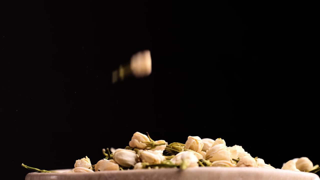 Dried Jasmine Flowers Falling into a Bowl
