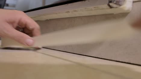 locked off close up of man laying masking tape on floor