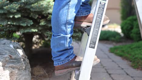 man climbs a ladder on a job site to repair a roof