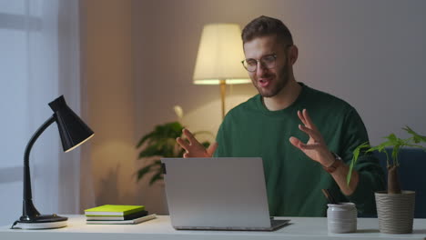 online communication by laptop young man is using internet from calling by video on notebook sitting at home at evening medium male portrait