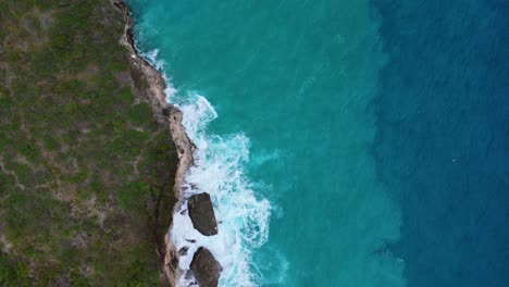 Drone-De-Arriba-Hacia-Abajo-A-Lo-Largo-De-La-Costa-De-La-Isla-Caribeña-Con-Arena-En-Resaca-Y-Caída-Azul-Profundo,-Vista-De-Pájaro