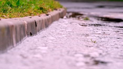 rainwater runs down concrete gutter towards drain after heavy downpour