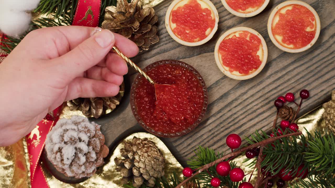 Hand Scooping Red Caviar from Bowl on Festive Holiday Table