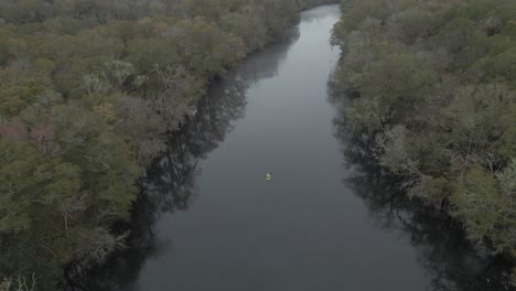 kayak verde remando lentamente en el centro de un río tranquilo en un día nublado en edisto