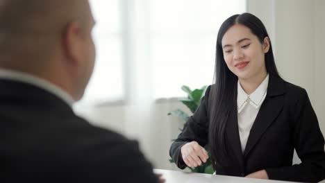 smart asian woman shakes hands to greet a hr staff before a job interview to apply for a job. happy woman seeker or insurance broker presenting a business deal. business woman sending resume.