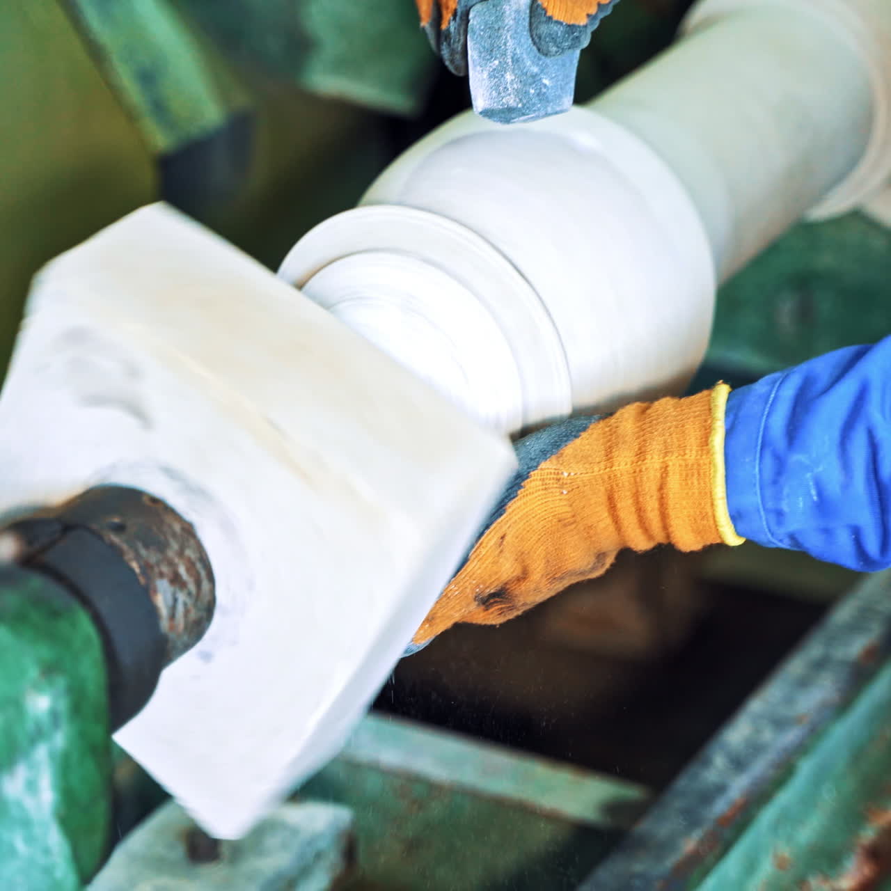 Man's hands in protective gloves polishing stone by grinder. Industrial tool is grinding rock in the factory. Hard work. Close-up.