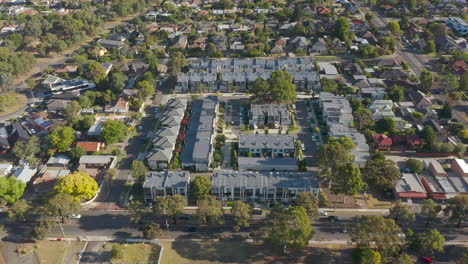 Smooth-parallel-tracking-along-roadside-with-modern-townhouse-development-highlighted-as-traffic-passes-by