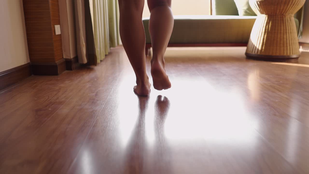 Person walking barefoot on a wooden floor