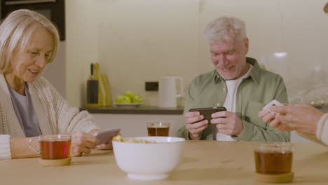 three senior friends playing game using their mobile phones at home 1