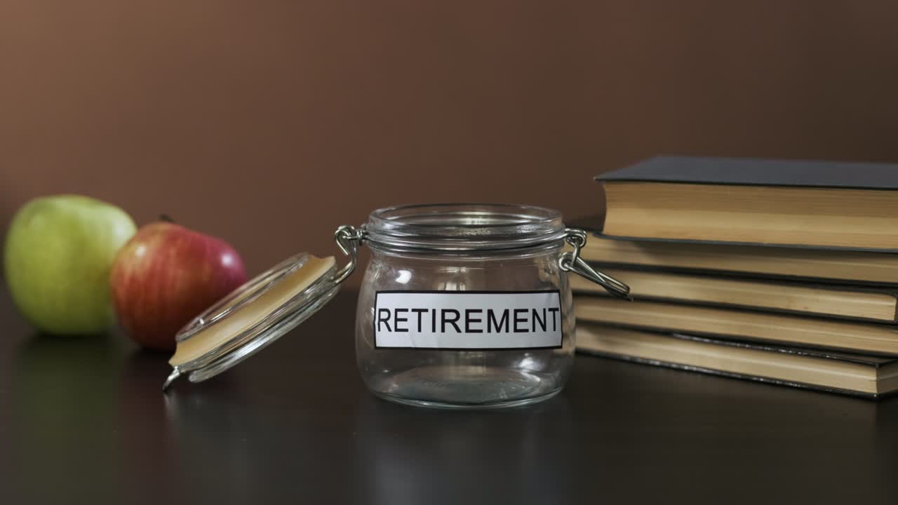 한 남자가 은퇴를 위한 저축을 위해 유리통에 돈을 넣습니다.