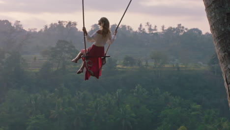 Mujer-Viajera-Balanceándose-Sobre-La-Selva-Tropical-Al-Amanecer-Turista-Sentada-En-Un-Columpio-Con-Vista-Panorámica-Disfrutando-De-La-Libertad-En-Vacaciones-Divirtiéndose-Estilo-De-Vida-De-Vacaciones-En-Cámara-Lenta