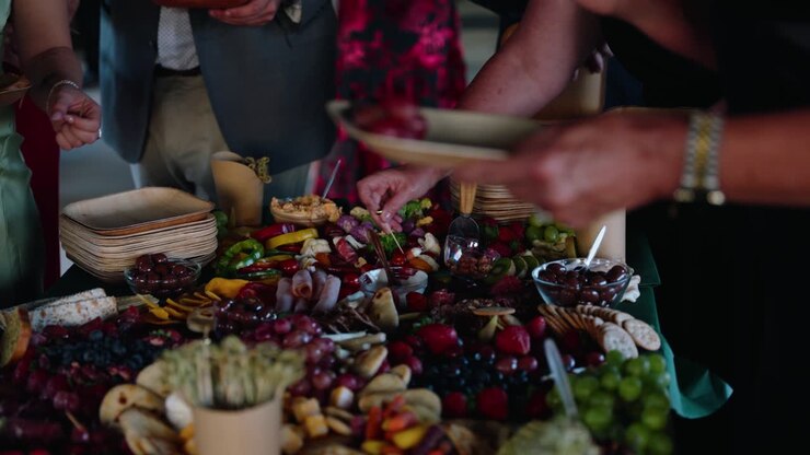 An inviting charcuterie spread during the cocktail hour at a fall wedding. Guests reach for food from a colorful table filled with fruits, cheeses, and snacks at a rustic winery venue in South Georgia