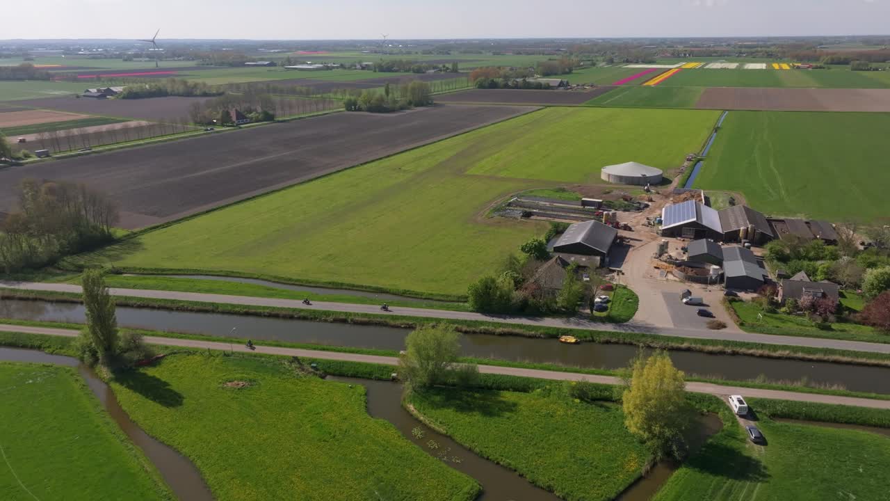 Vista aerea di una strada di campagna con motociclette che passano tra verdi prati, Olanda.