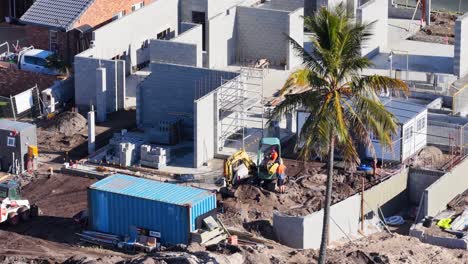 drone footage captures workers and machinery at a construction site under bright daylight in gold coast, australia