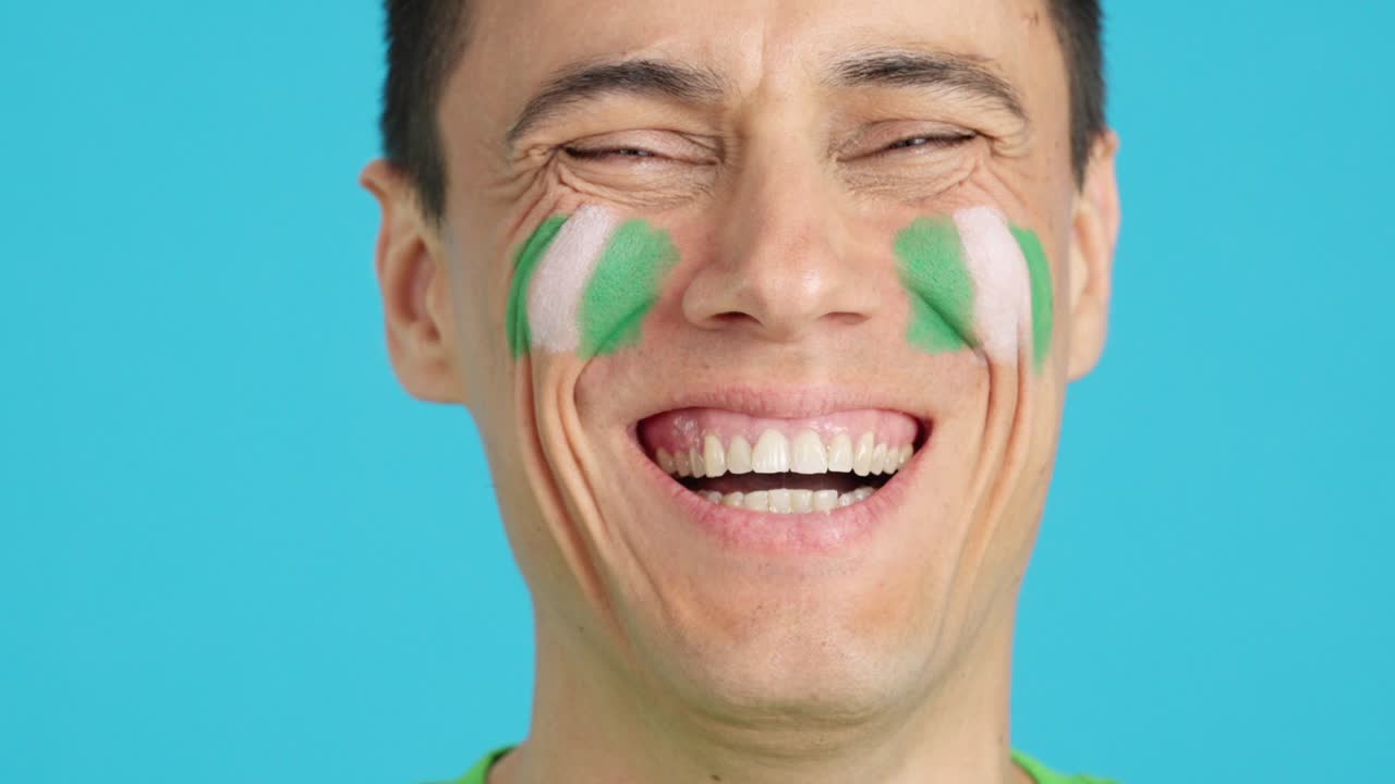 Man with a nigerian flag painted on the face smiling