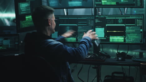 hacker or programmer working on multiple computer screens in a dark room