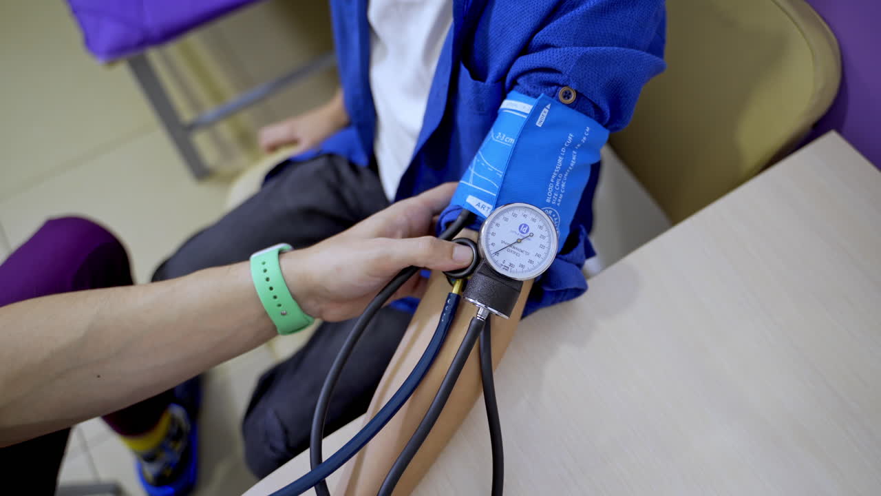 Pediatrician is measuring blood pressure of boy teenager. Selective focus on apparatus. Pediatric concept.