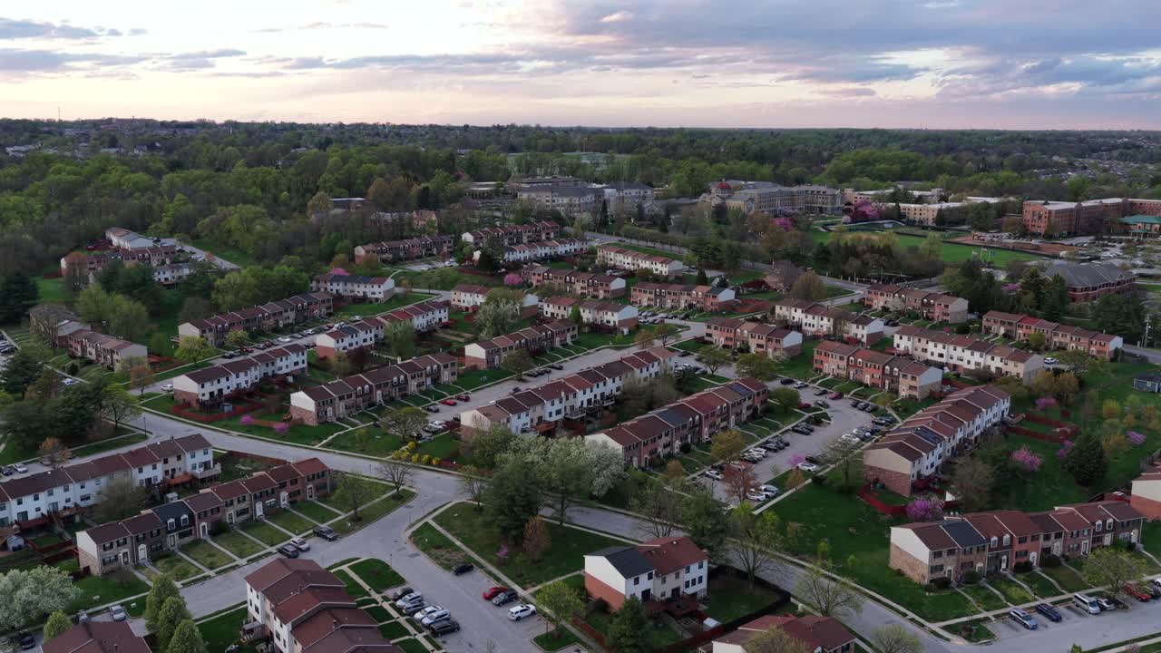 Aerial rising view of an American suburban neighborhood at sunrise, with rows of townhouses, tree-lined streets and soft spring light. Calm residential life in USA. Baltimore, Maryland