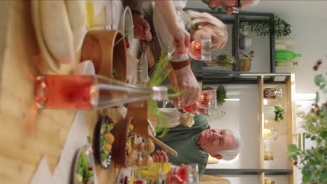 joyous senior friends toasting with drinks at festive dinner