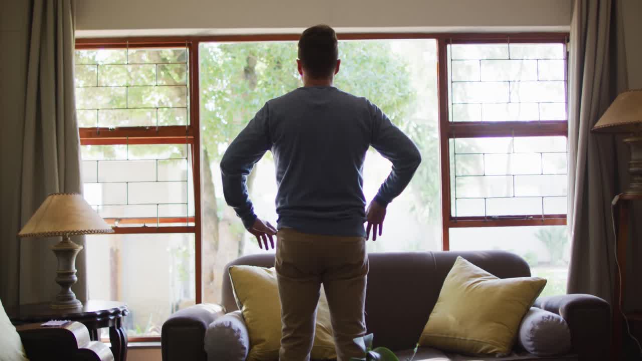 집 의 창문 에 서 있는 사려 깊은 백인 남자 의 뒷면