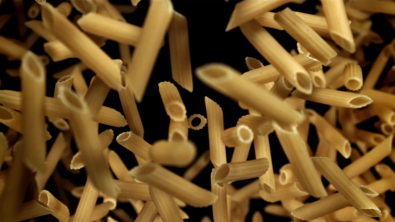 Primo piano di pasta penne secca che cade al rallentatore