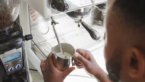 primer plano de un barista afroamericano haciendo café usando una máquina de café en una cafetería