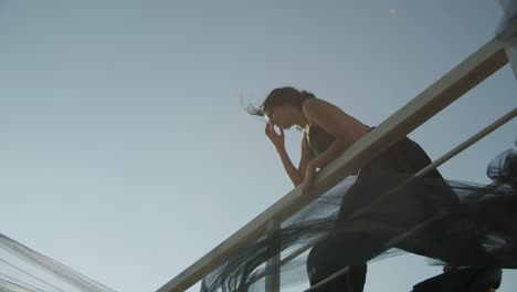 Beautiful-Woman-In-Black-Dress-Posing-While-Standing-And-Leaning-On-Railing---Low-Angle