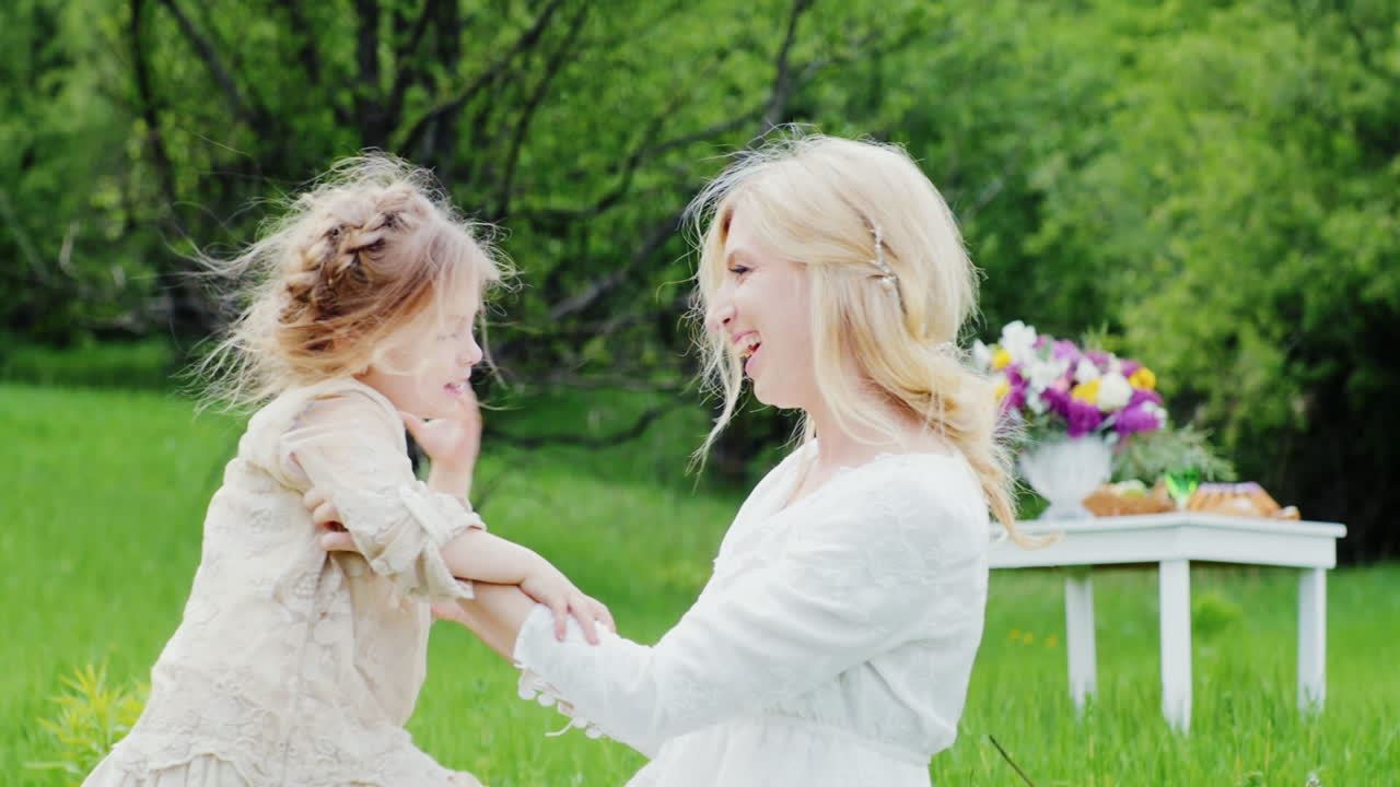una madre joven con estilo con el pelo rizado juega con su hijo en el jardín se ríe y se divierte