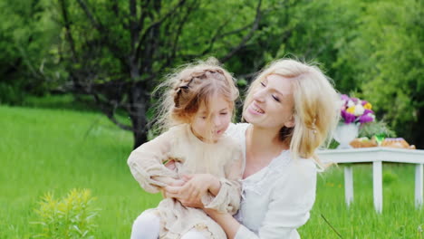 a stylish young mother with curly hair plays with her child in the garden laughs and has fun