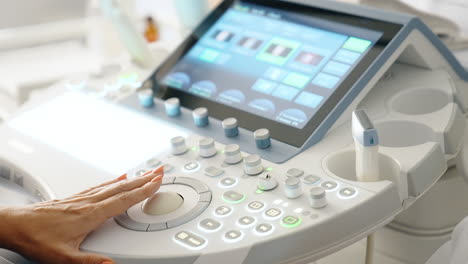 female hand operating the modern ultrasonic equipment. doctor presses buttons on the keyboard. close up.