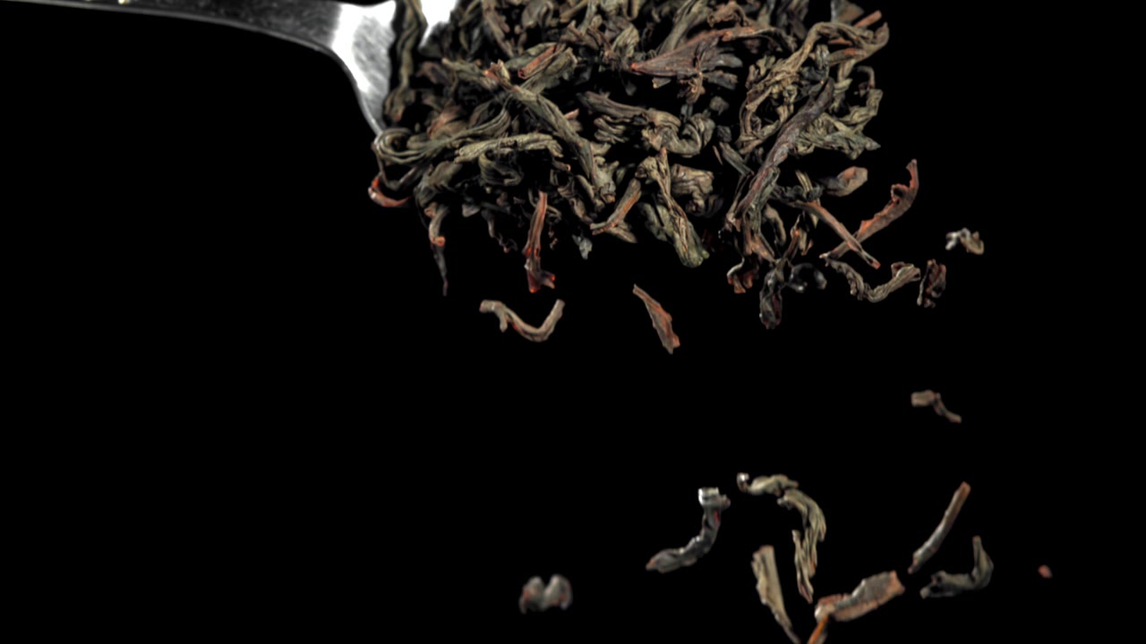 Dry Tea Leaves Pouring from a Spoon in Slow Motion
