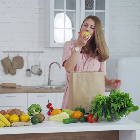 happy housewife with fresh fruit and vegetables in the kitchen. young woman unpack organic food from paper bag at home.