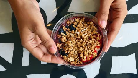 person holding a delicious acai bowl with granola and berries