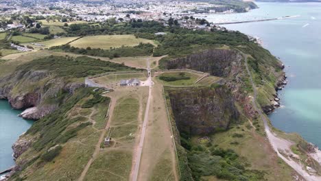 Antena-Volando-Hacia-Atrás-Por-Encima-De-La-Cantera-Con-Brixham,-Devon-En-Segundo-Plano.