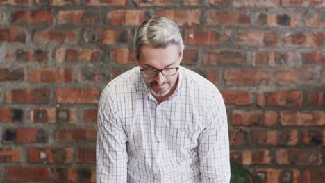 Busy-caucasian-casual-businessman-leaning-on-desk,-looking-up-and-smiling