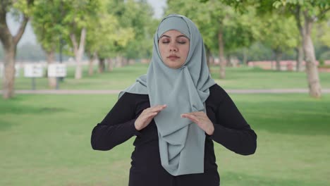 happy muslim woman doing yoga in park