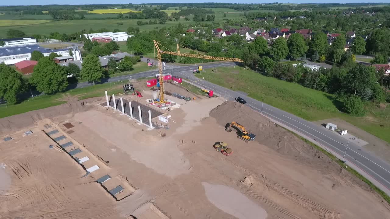 A drone flies over a large construction site on which a huge production hall is being built