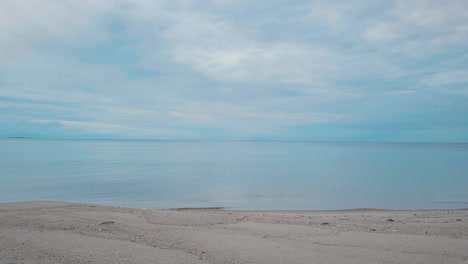 Toma-De-Conducción-Pov-A-Lo-Largo-De-La-Playa-De-Arena,-Océano-Azul-Infinito-Y-Cielo-Nublado