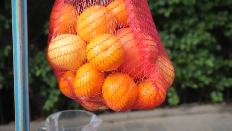 fresh orange fruits in a red basket, oranges on a blurred greenery background