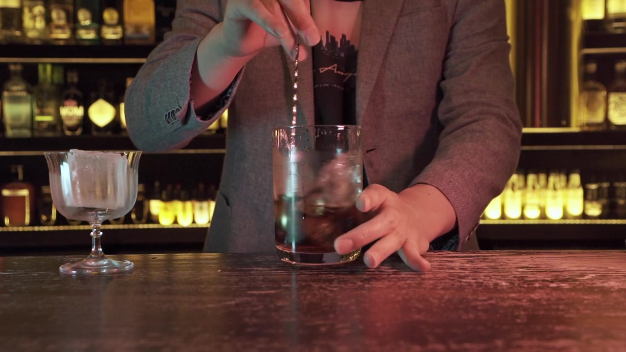 Sej, trendy bartender rører cocktail i bar i slowmotion