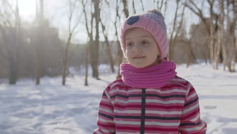 smiling child kid girl tourist walking, having fun on snowy road in winter sunny park forest, sunset