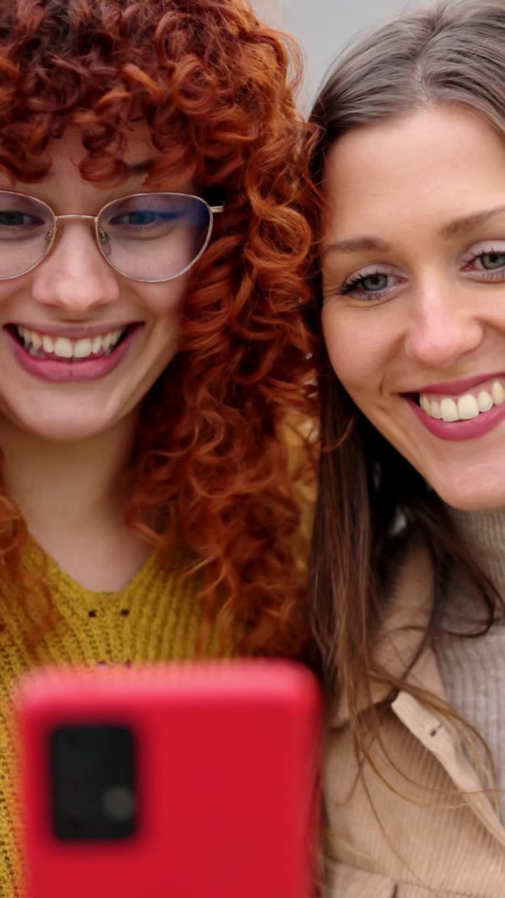 Amici donne che ridono mentre usano il telefono insieme